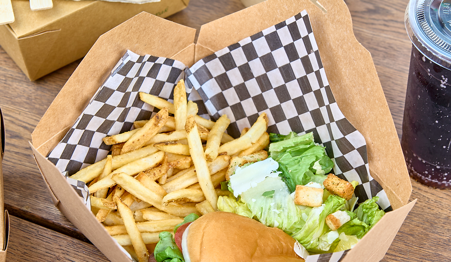 Fast food meal with fries, burger, and drink on a wooden table